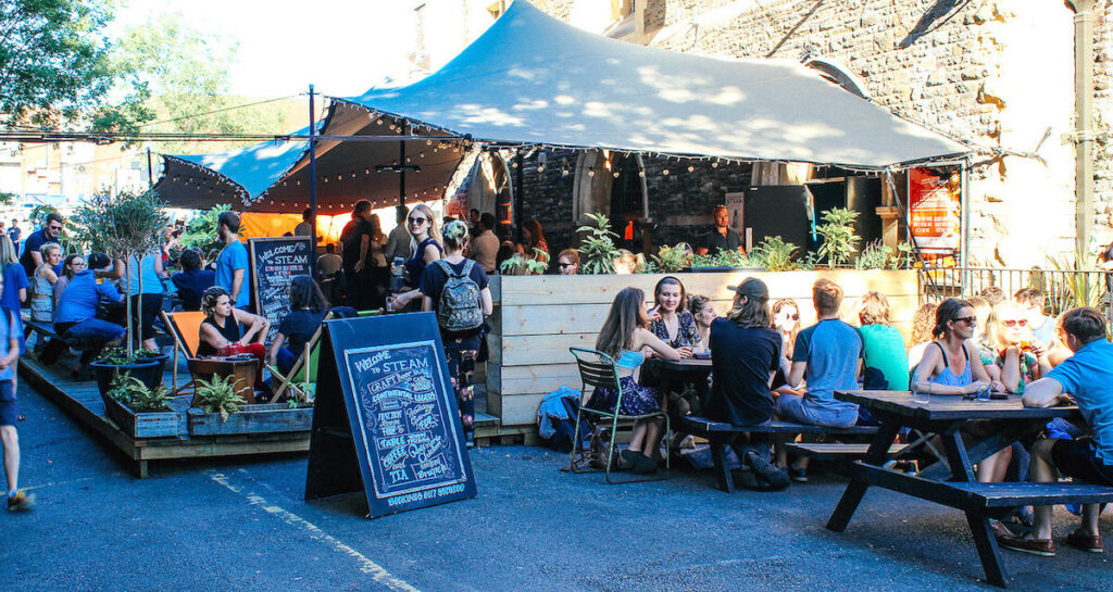 Steam Bristol's covered terrace with stretch tents, lounge furniture, and people socialising outdoors